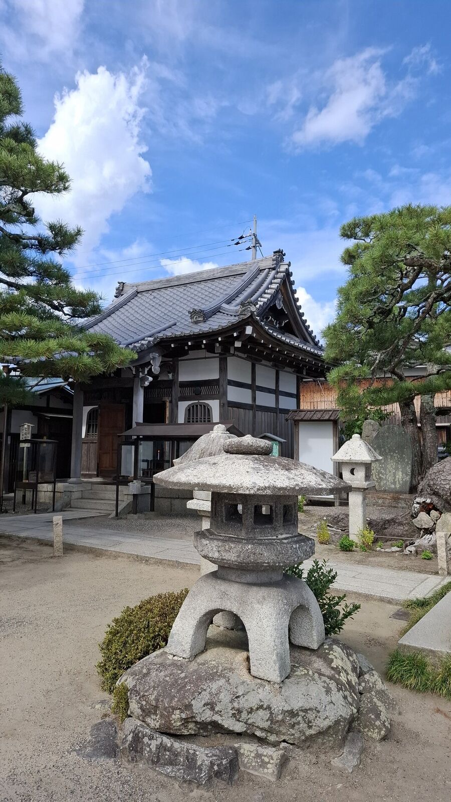 Mangetsu-ji main hall with stone lantern in the foreground and pine trees flanking the courtyard