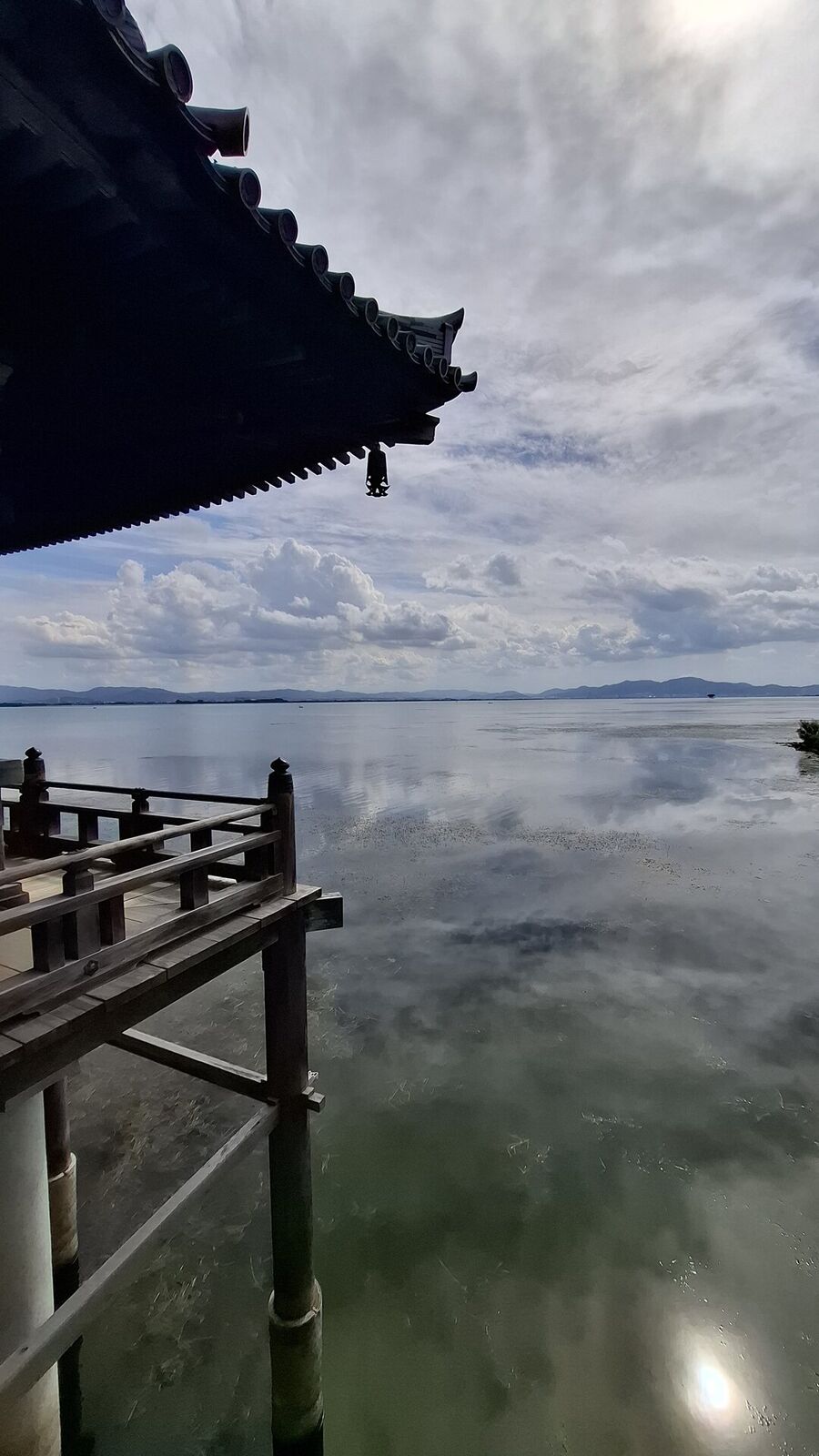View from inside the Ukimido: the temple roof silhouetted against dramatic clouds over Lake Biwa, water reflecting the sky