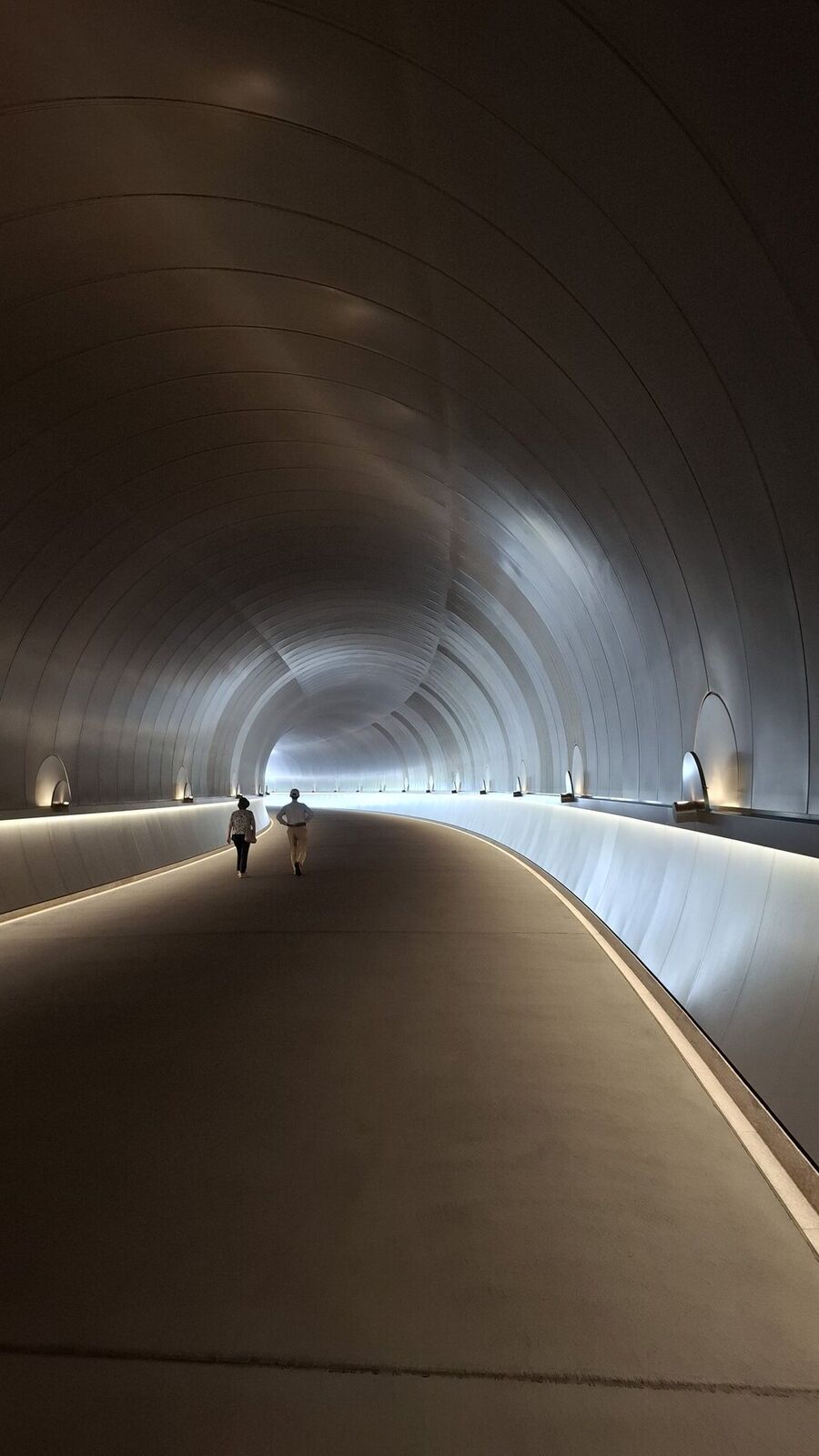 The tunnel's copper-clad walls from a diagonal angle, warm tones catching the light as the passage curves away