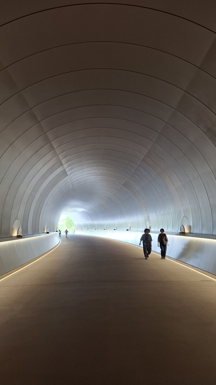 Silhouettes of visitors at the tunnel exit, bright daylight pouring in from the bridge beyond