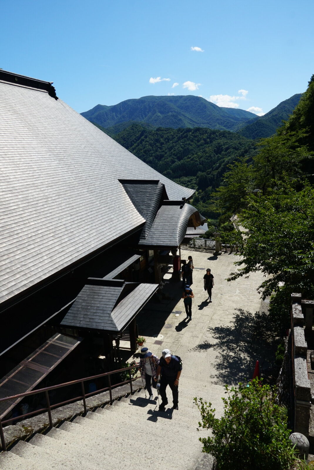 The Godaido terrace area with buildings and visitors, mountains forming the dramatic backdrop