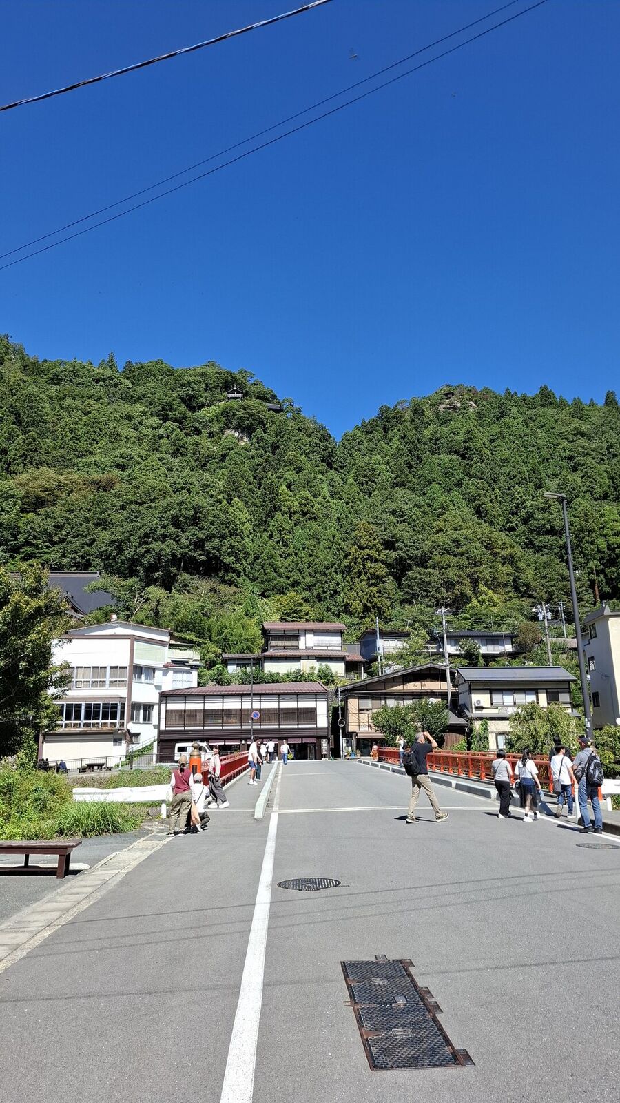 The small town of Yamadera at the base of the mountain, forested peak rising behind traditional buildings under blue sky