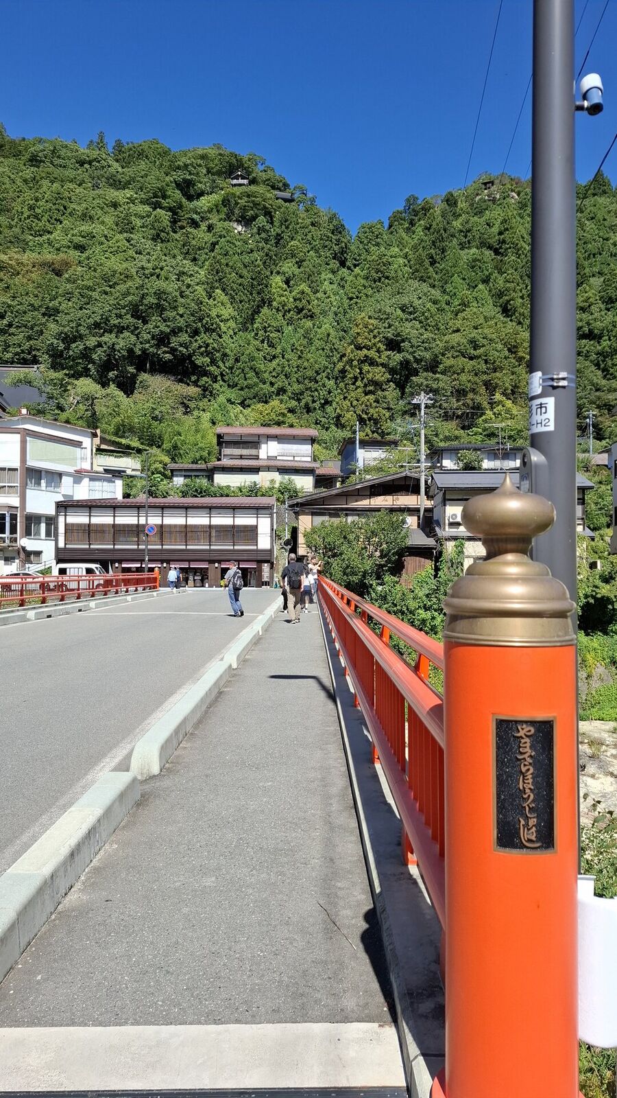 The orange bridge at the base of Yamadera with temple mountain rising above, marker posts lining the road