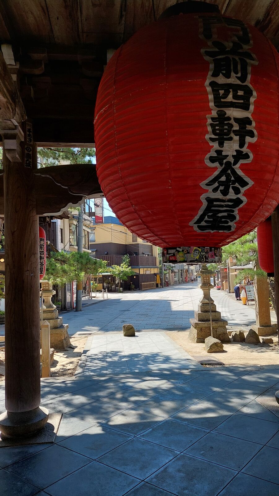 The entrance gate of Chionji temple framed by a giant red paper lantern with black kanji, the temple courtyard and stone lanterns visible beyond