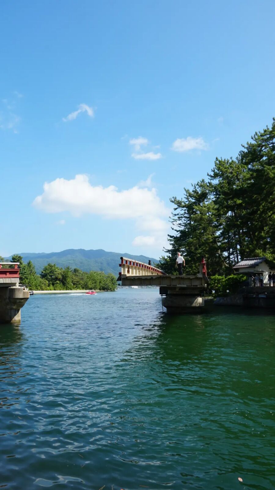 The rotating bridge and canal at Amanohashidate, calm turquoise water reflecting the bridge structure and surrounding pines
