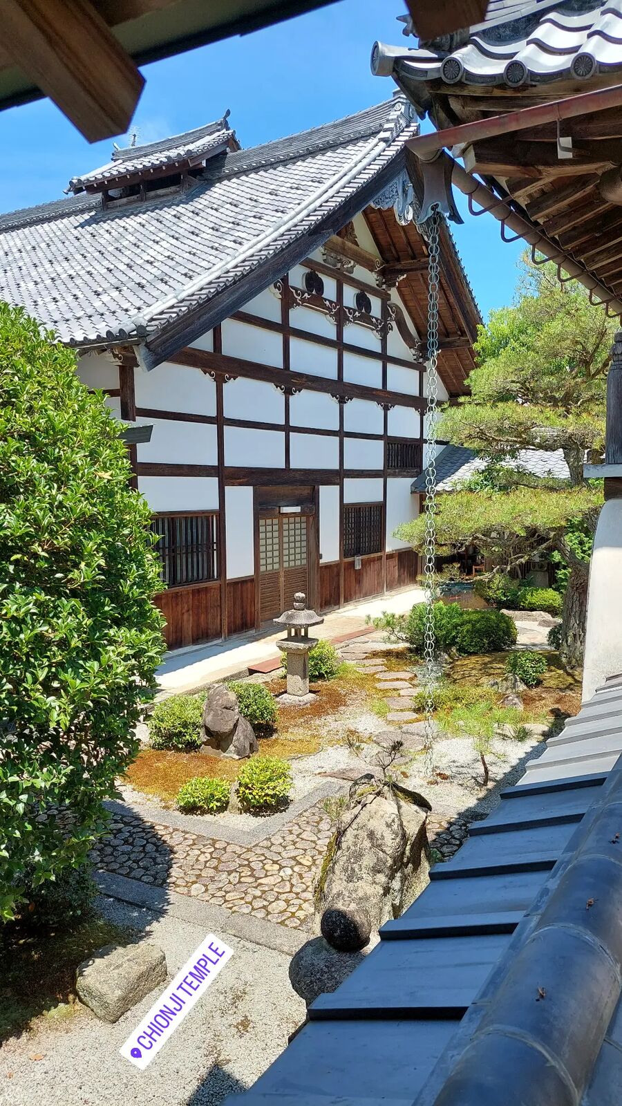A traditional Japanese temple building at Chionji with white walls and dark wooden framework, a small zen garden with stepping stones in the foreground