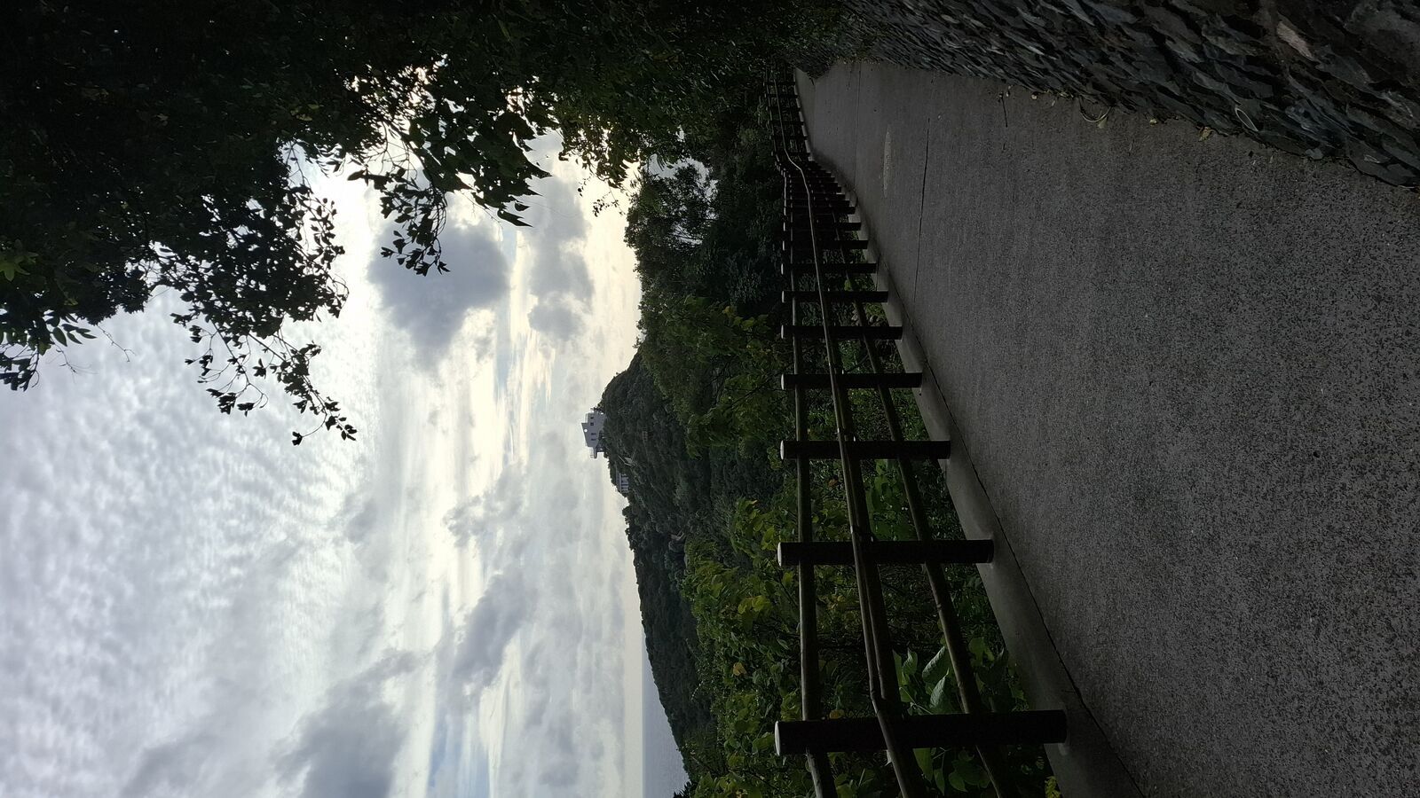 The path to Cape Sata along a concrete wall with dramatic cliffs and ocean to the left, clouds building overhead