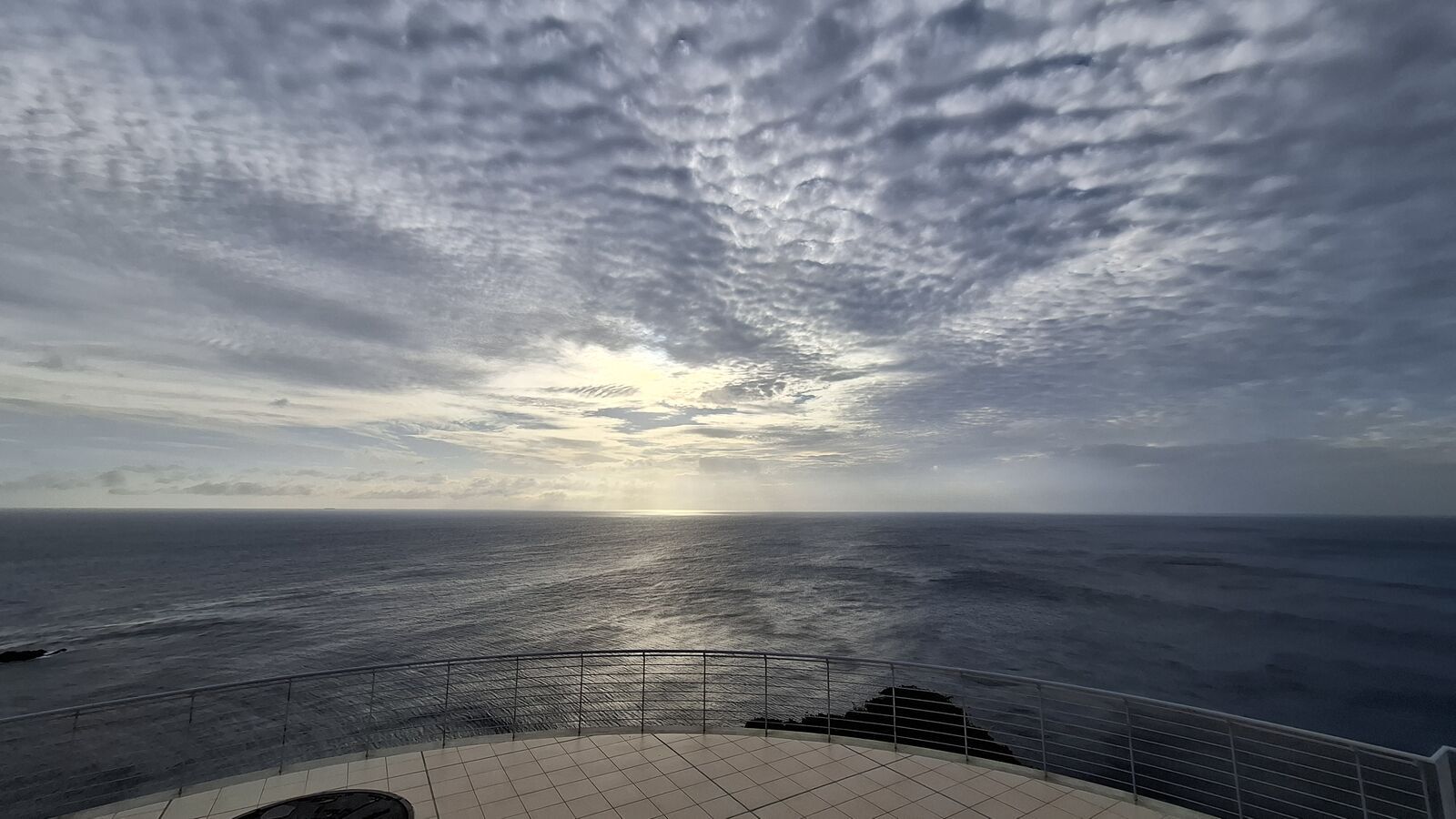 Panoramic view from the observation platform at Cape Sata, sun breaking through clouds onto the ocean, cliffs falling away on both sides