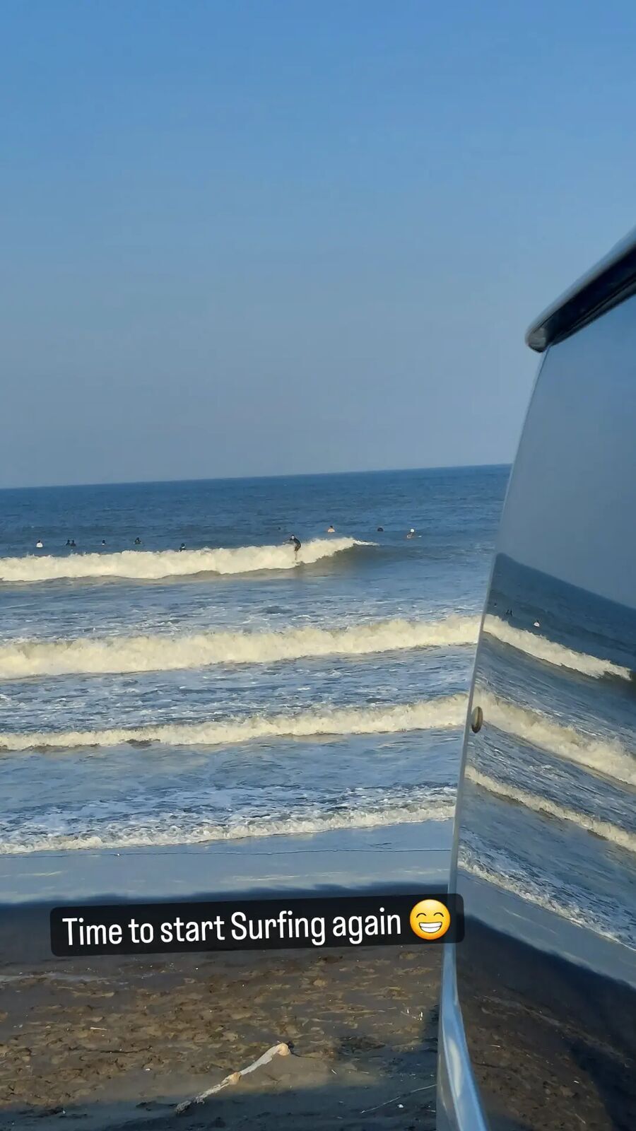 Van window reflecting the ocean with surfers in the waves, afternoon light on Chiba's Pacific coast
