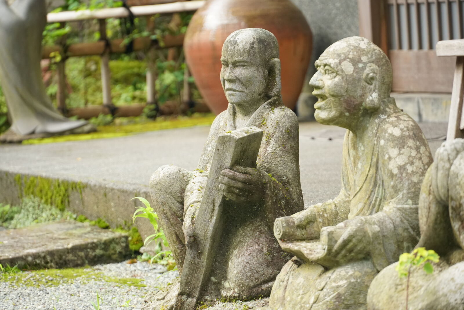 Two rakan figures sitting together, one reading a book while the other peers over his shoulder, both deeply absorbed