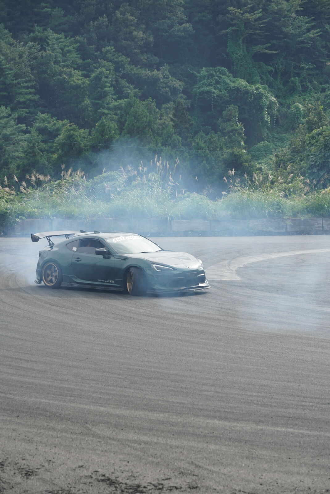 Drift car trailing a dramatic cloud of tire smoke at Ebisu Circuit