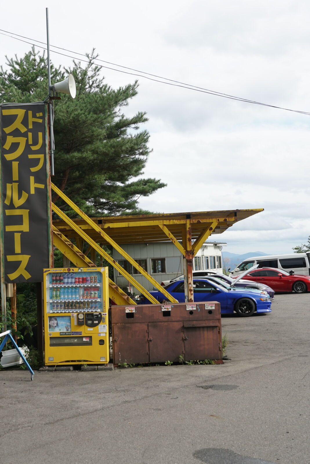 Drift School Course sign on yellow metal viewing tower with vending machine at the base