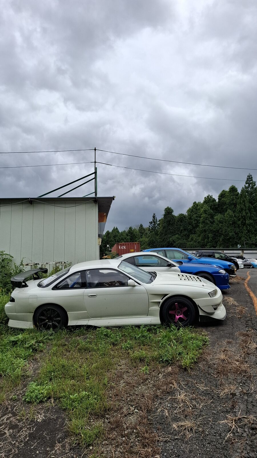 White sedan with pink aftermarket wheels parked in the lot