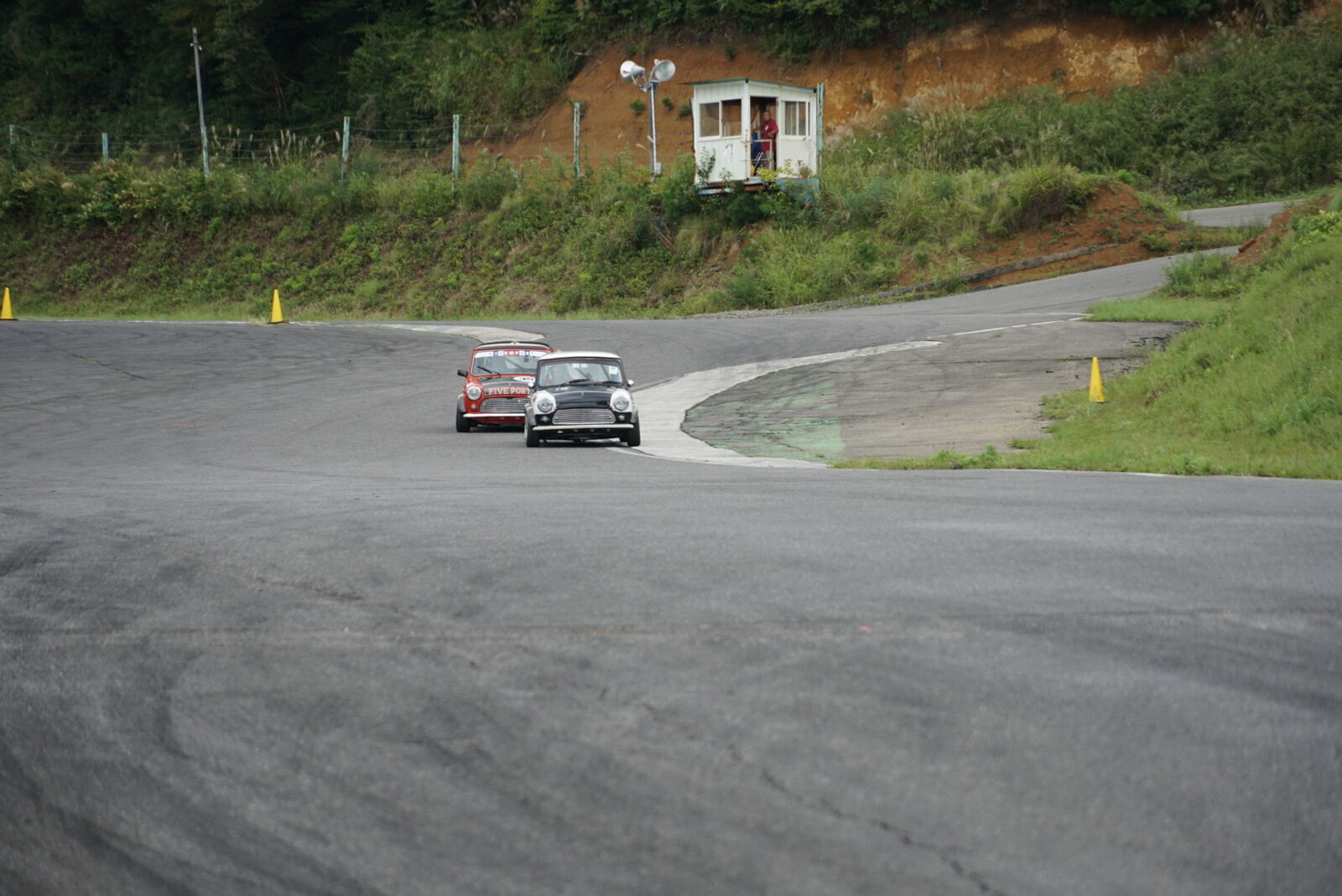 Classic Minis chasing through the banked curve from a different angle