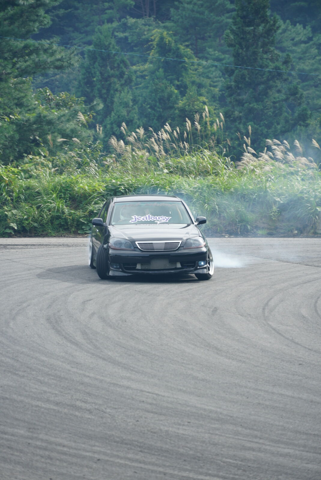 Car approaching the drift course at the edge of the dense forest