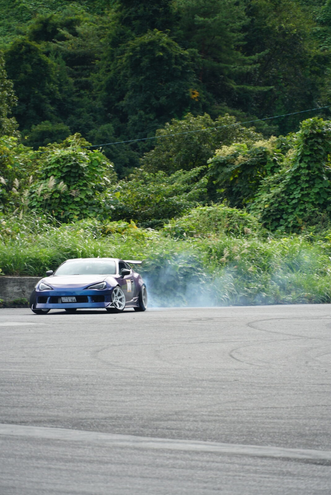 Blue car in a controlled slide across the drift pad