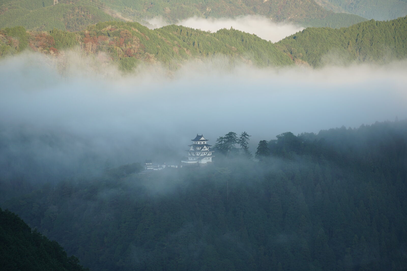 Atmospheric view of the castle with thinning clouds creating depth and layers