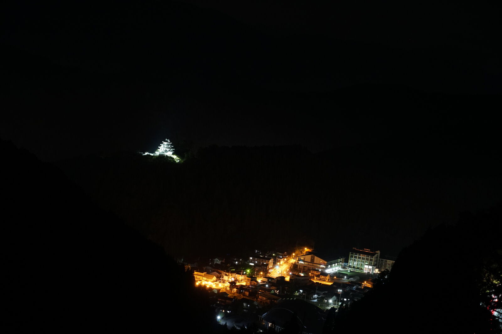 Night view of Gujo Hachiman with the illuminated castle on the hilltop and warm town lights in the valley below