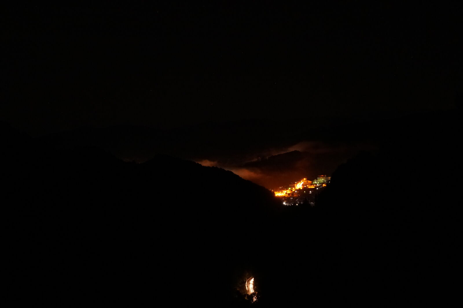 Pre-dawn view with town lights visible through gathering fog in the valley