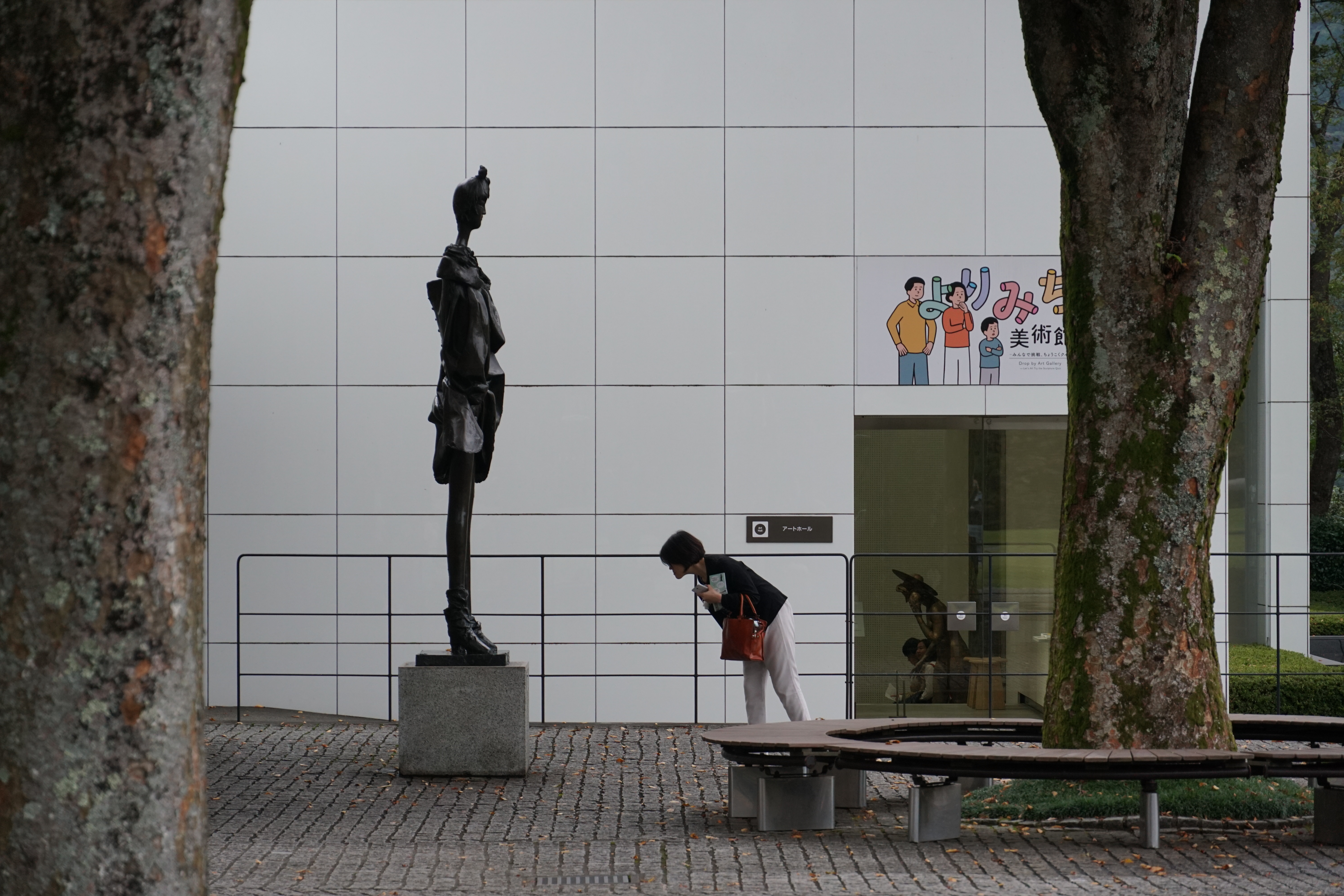 Standing bronze figure with modern museum building behind