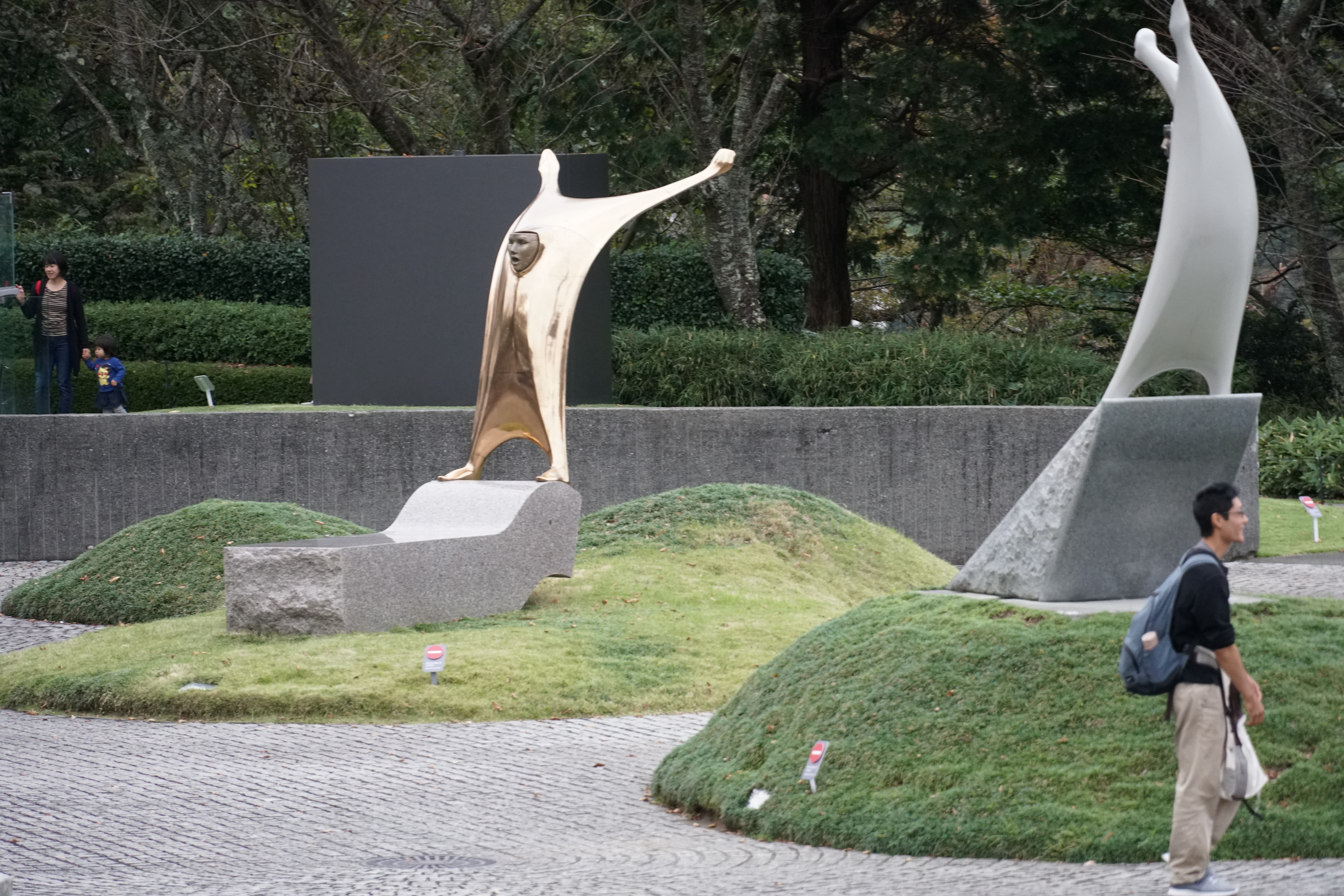 White abstracted figure sculptures on mounded landscape