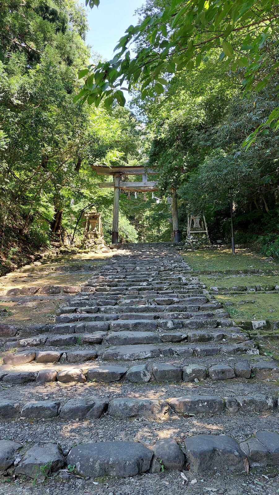 The ancient stone steps of the medieval approach road leading up through the summer forest, stone retaining walls on both sides