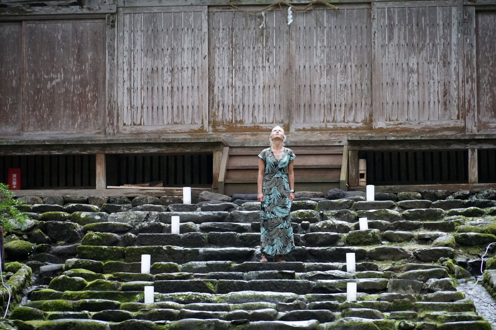 Standing on the moss-covered stone steps before the main shrine, looking up at the ancient wooden building
