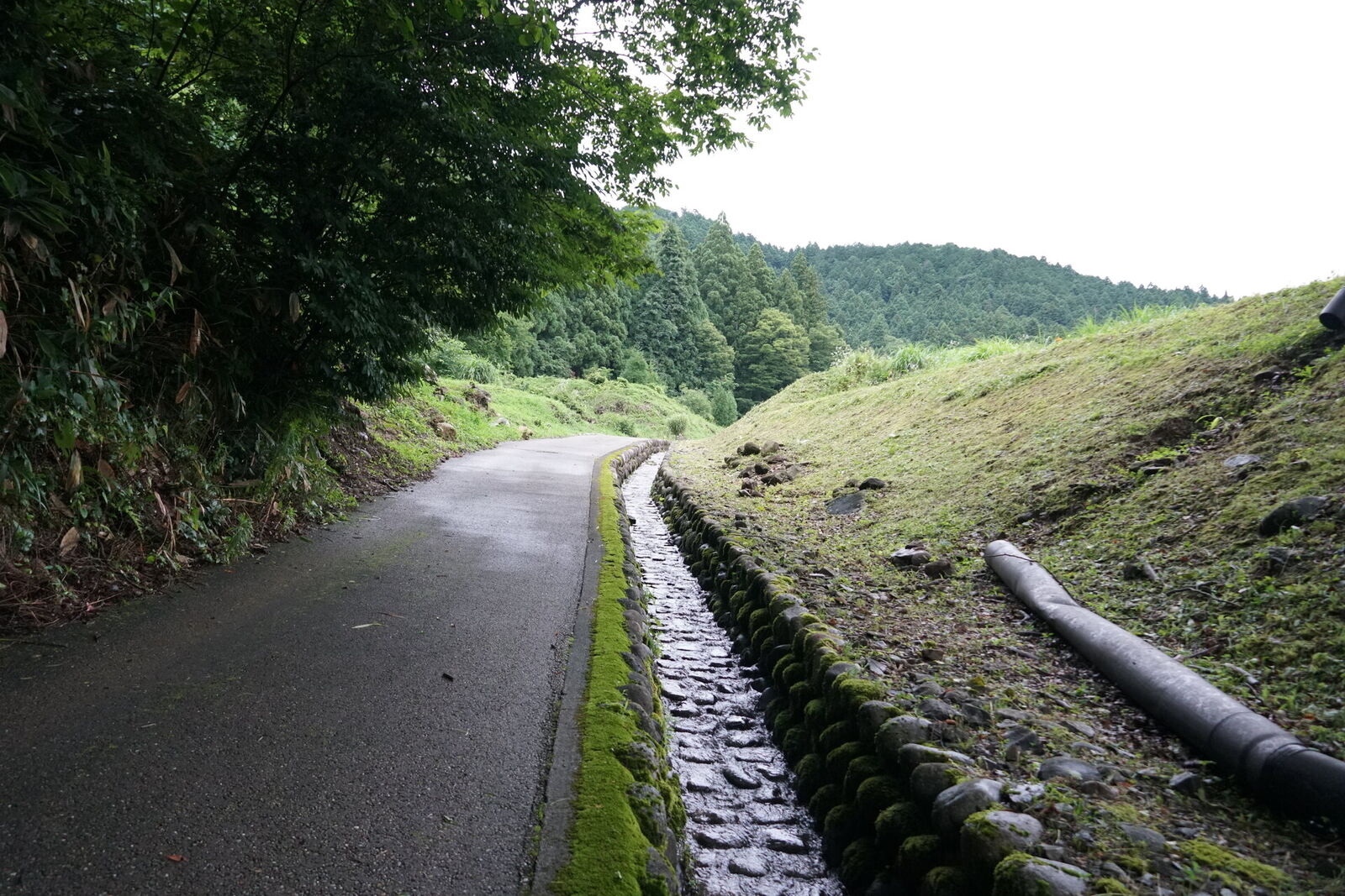 The modern paved road running alongside the original medieval stone-block access road, a thousand years of engineering side by side