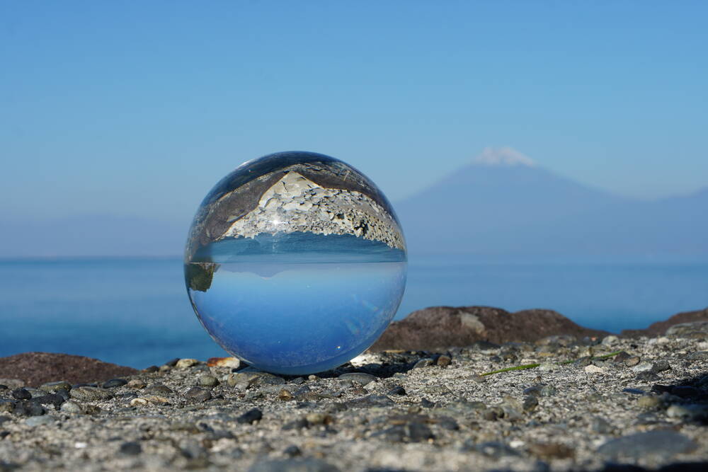 Mount Fuji seen through a glass lensball on the pebble beach at Heda, the mountain reflected upside down