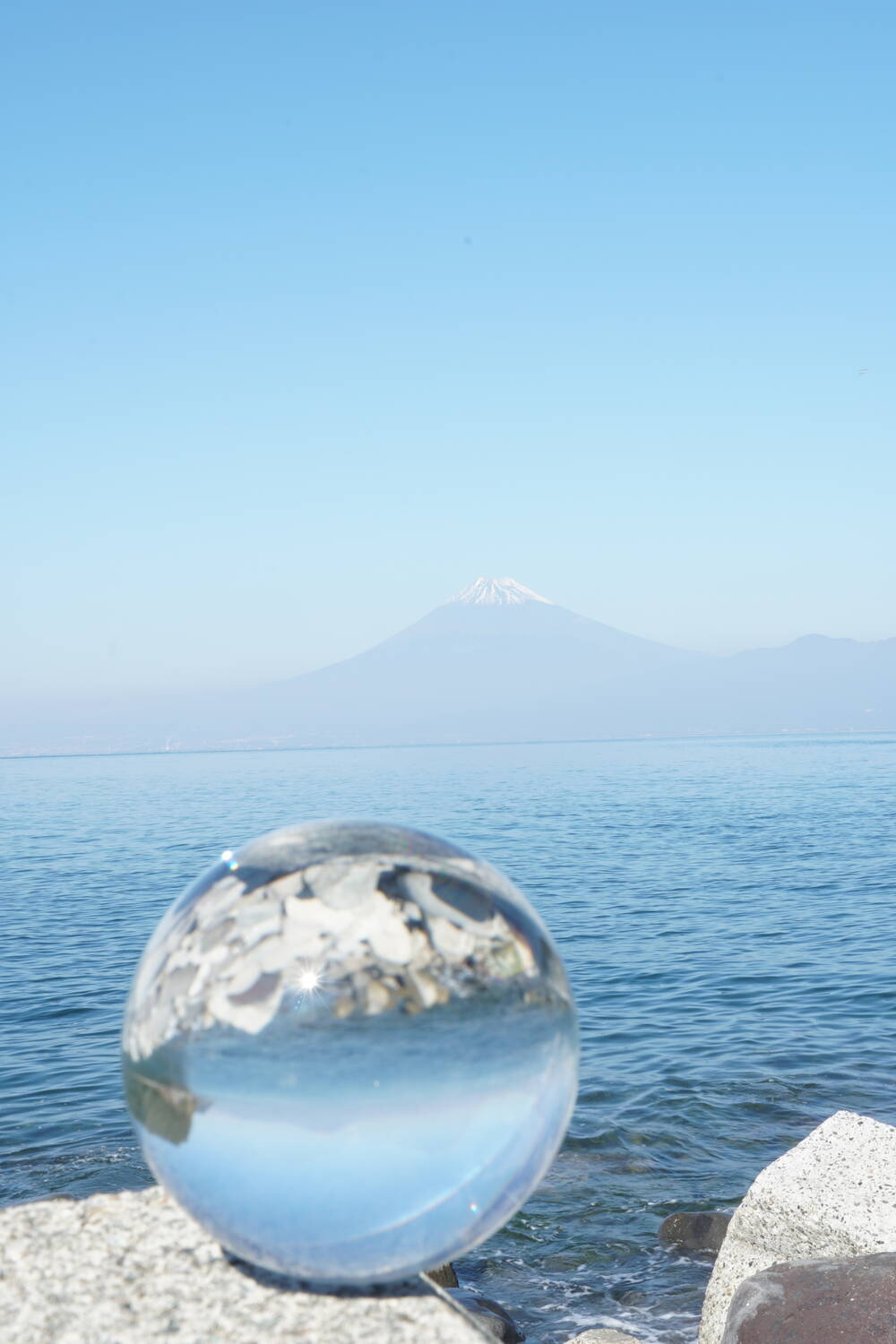Mount Fuji reflected vertically through a glass lensball lens on the Heda shoreline