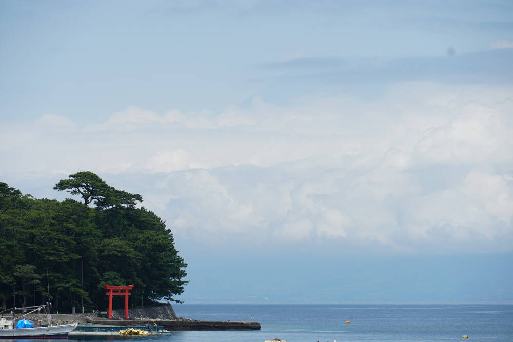 Red torii gate on the pine-covered shrine peninsula at Heda, fishing boats in the foreground