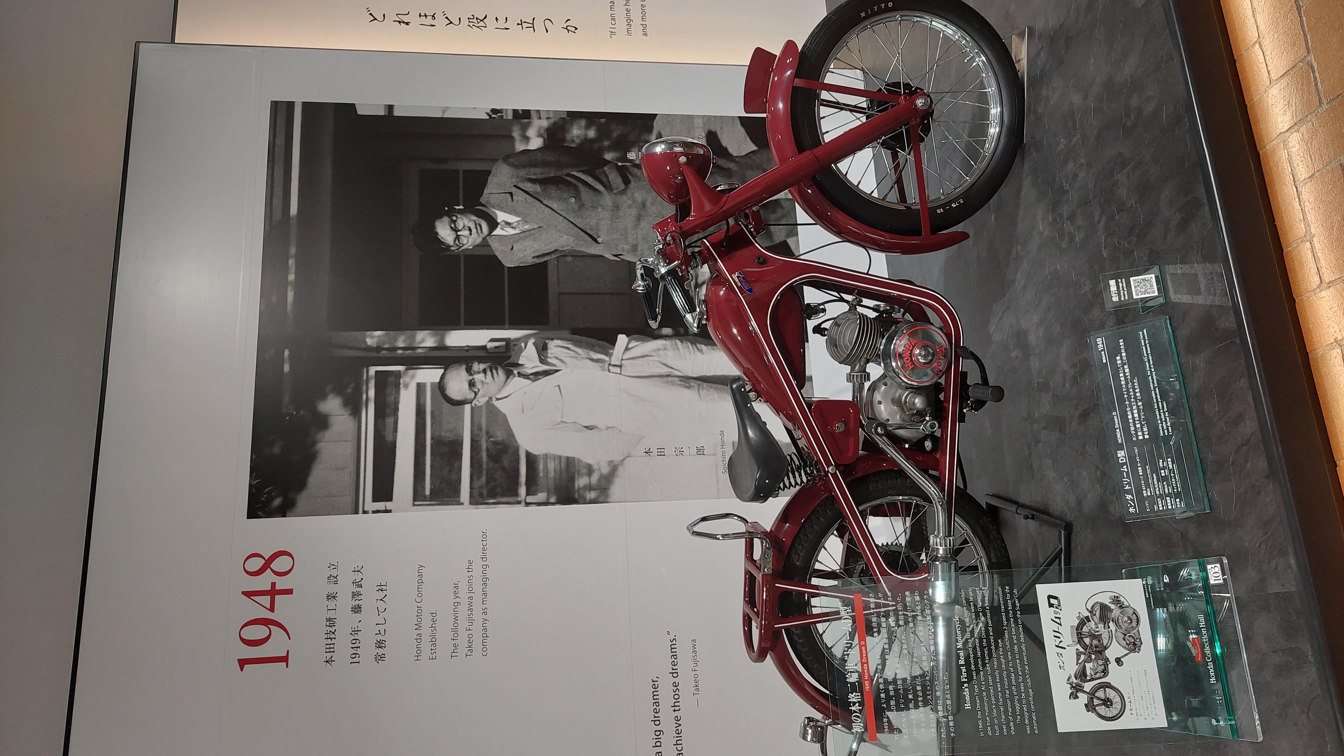 Honda Dream D-Type from 1948, the red motorized bicycle next to Soichiro Honda's photograph