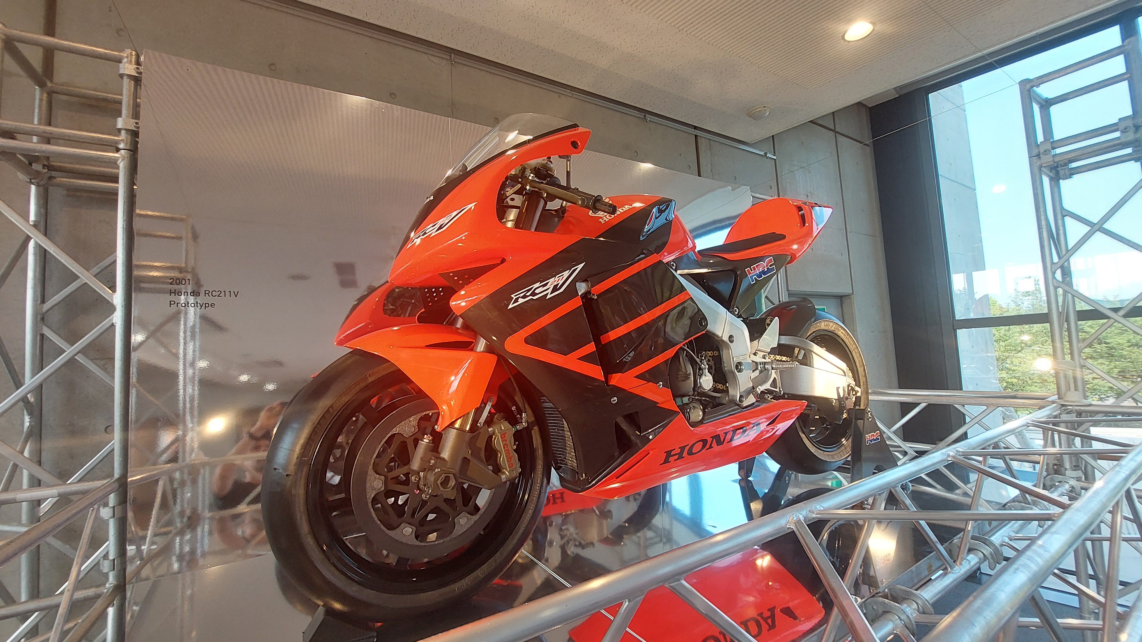 Orange Honda CBR motorcycle mounted on scaffolding display, an unusual presentation angle