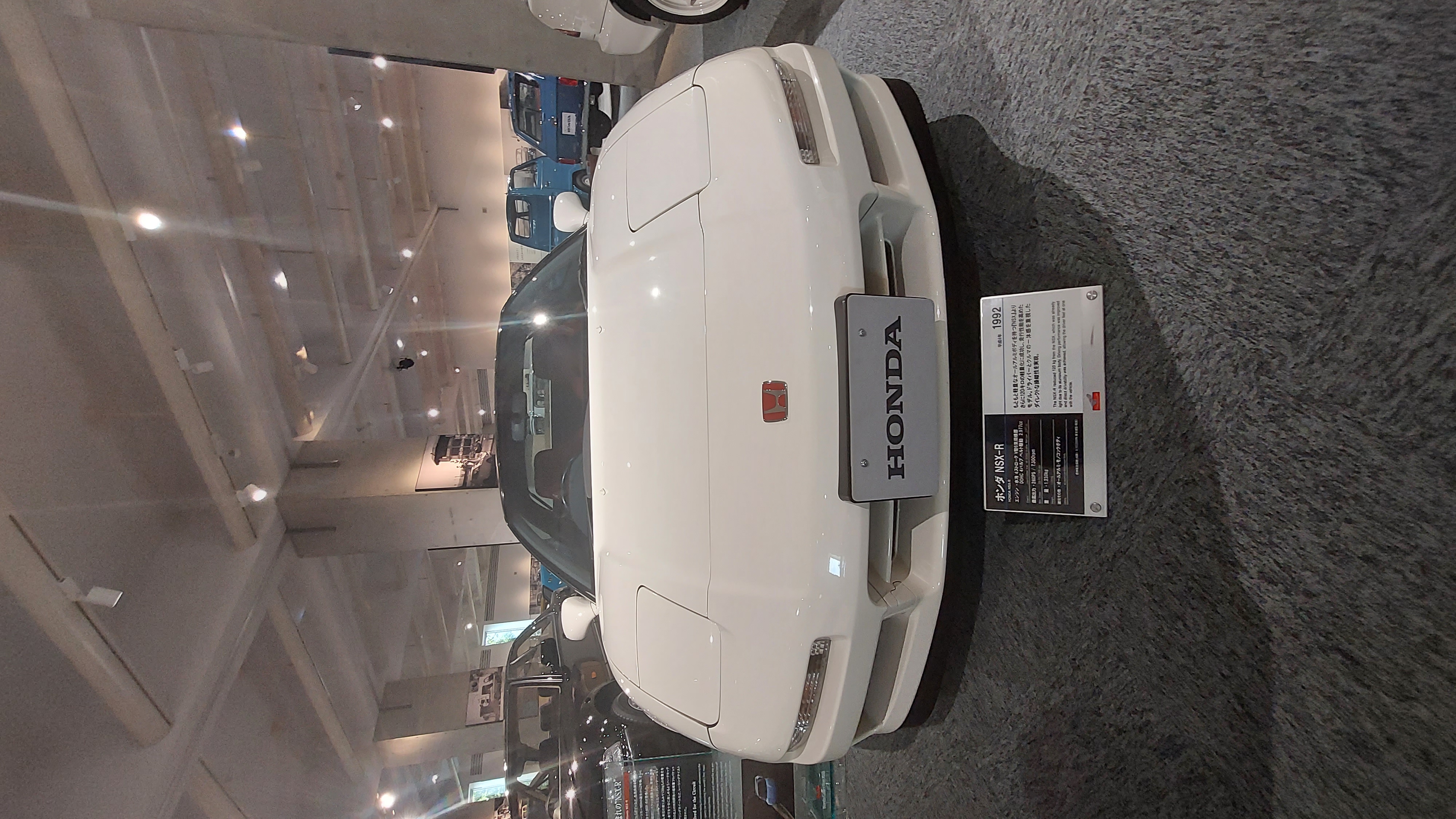 Honda NSX front view with the red H badge, Championship White paint gleaming under museum lights