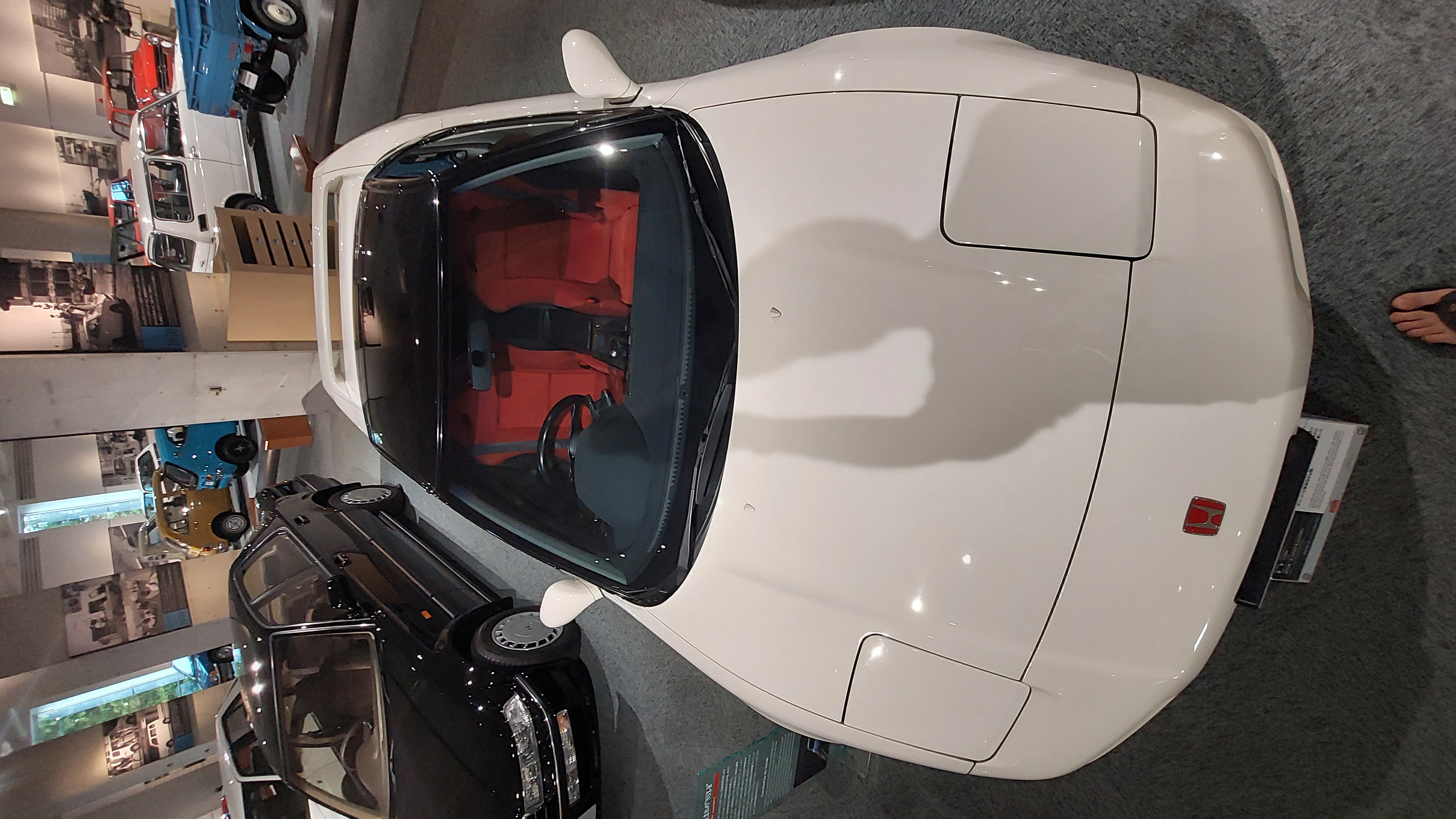 White NSX from above showing the red interior through the glass roof, with other cars visible around it