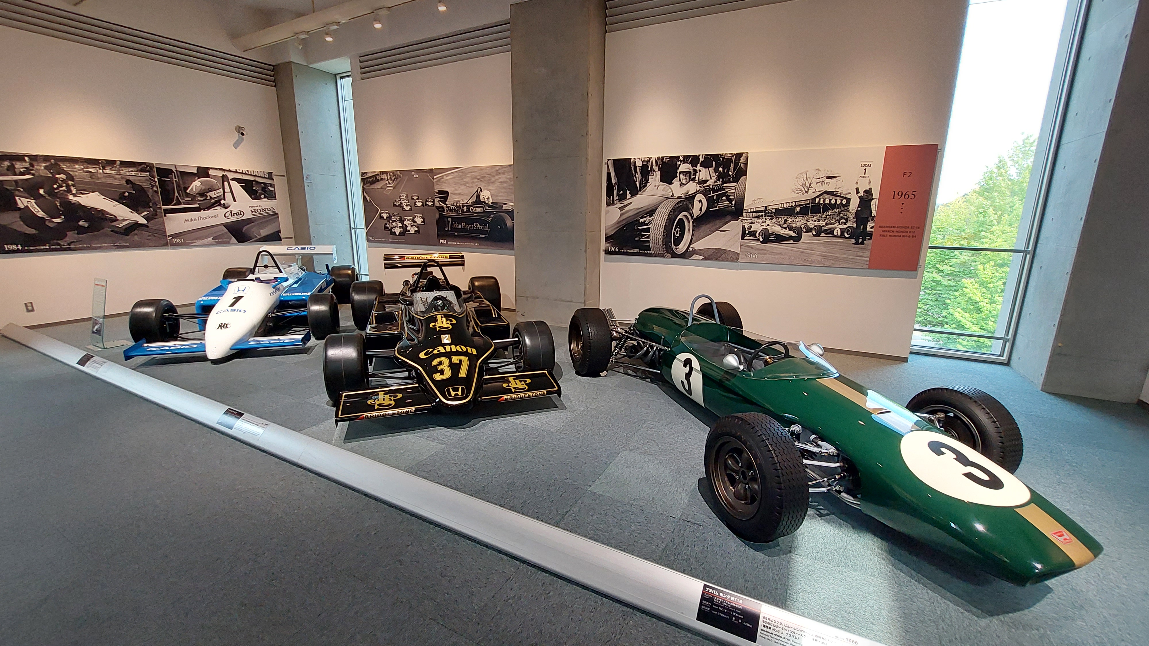 Three historic F1 cars side by side: green Brabham, black and gold JPS, and blue Ligier, all Honda-powered