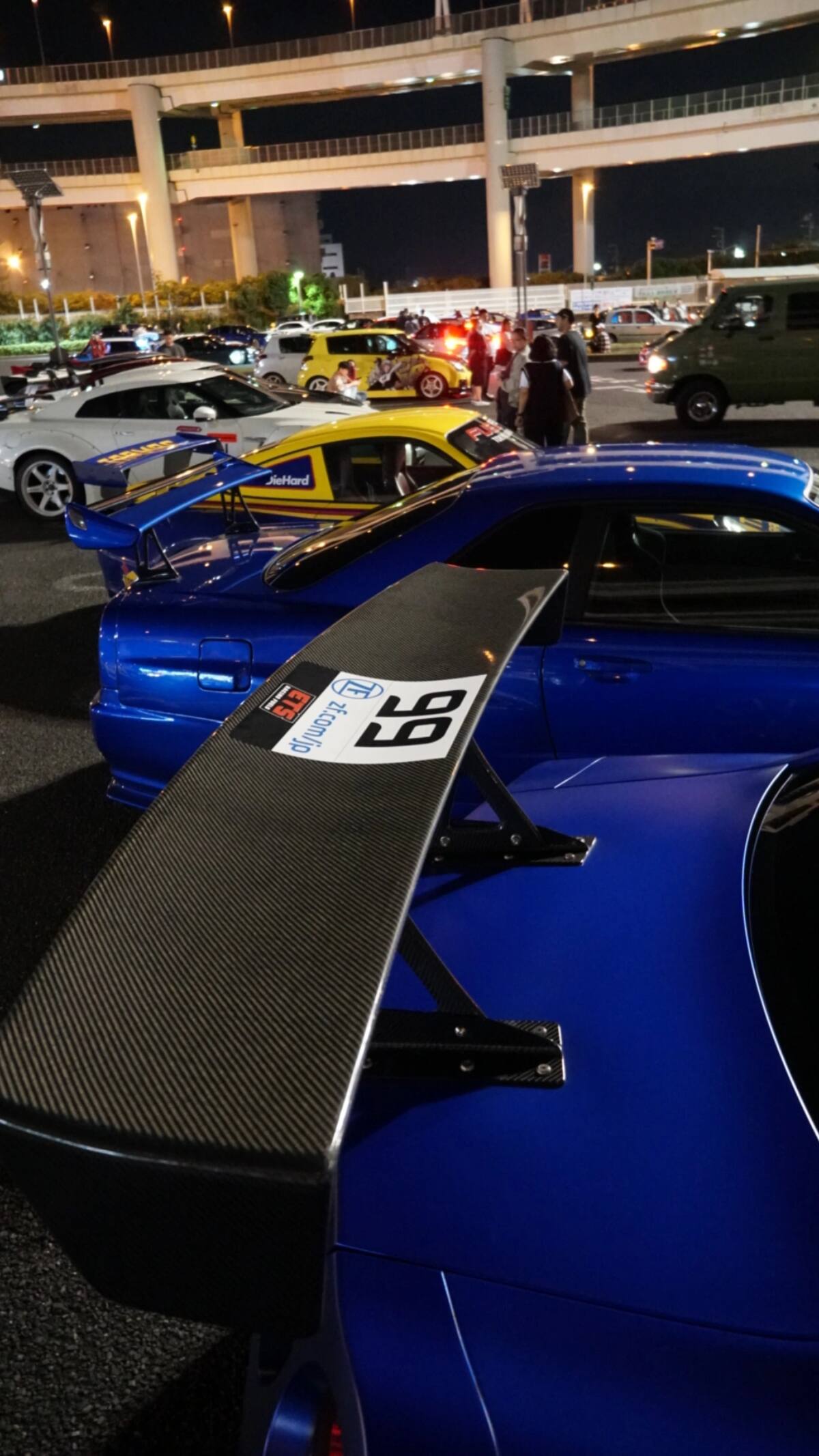 GT-R #99 carbon wing detail with Daikoku PA and cars in the background