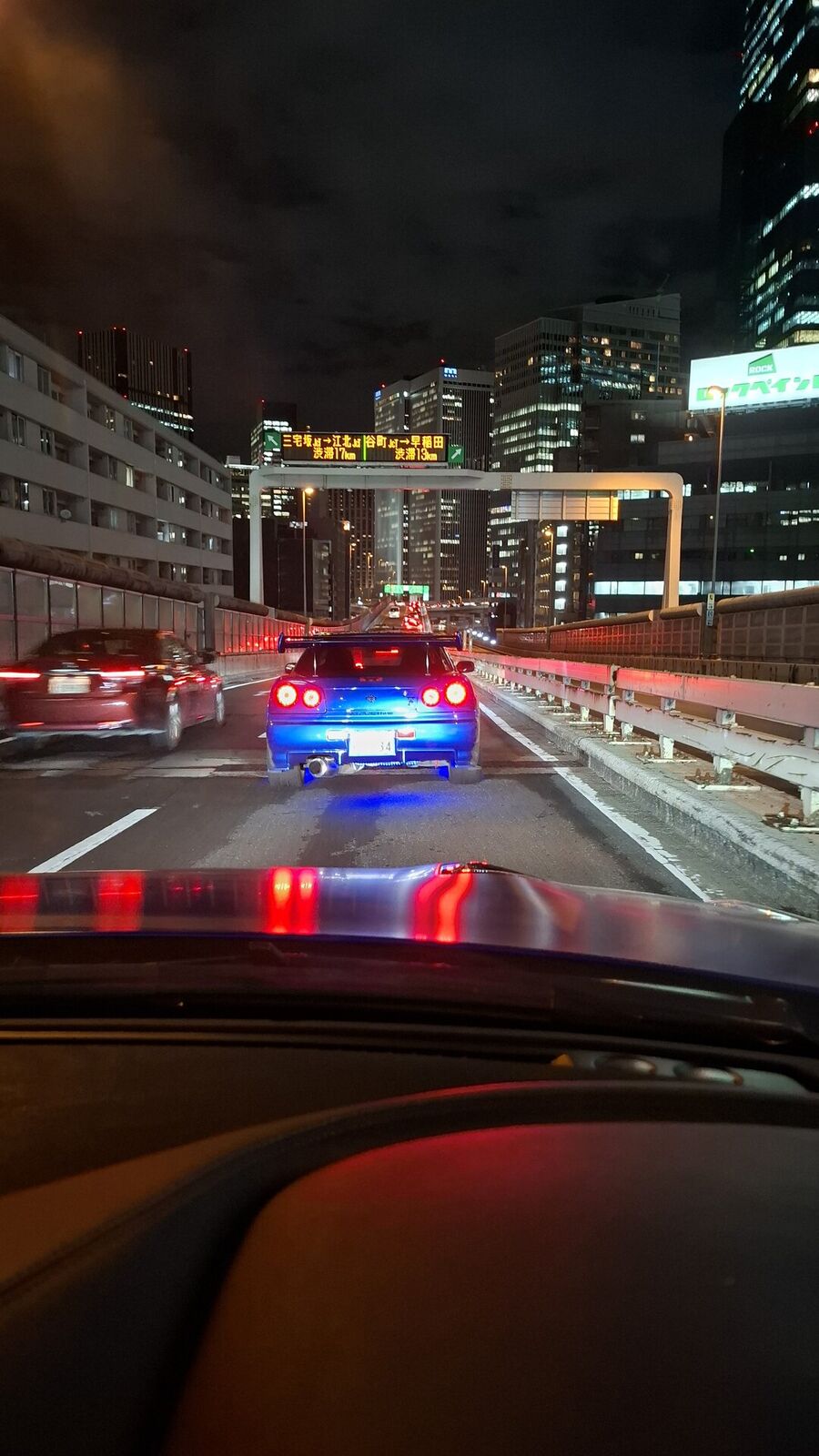Following the GT-R through Tokyo at night, its round taillights glowing blue and red against the city lights and skyscrapers