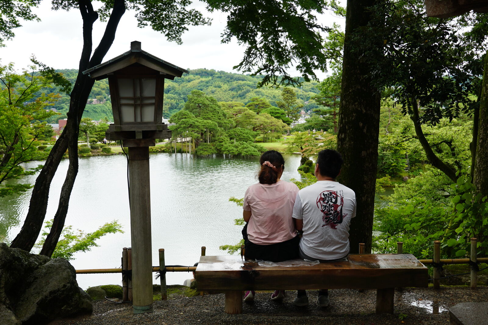Couple resting on a garden bench with stone lantern and pond view