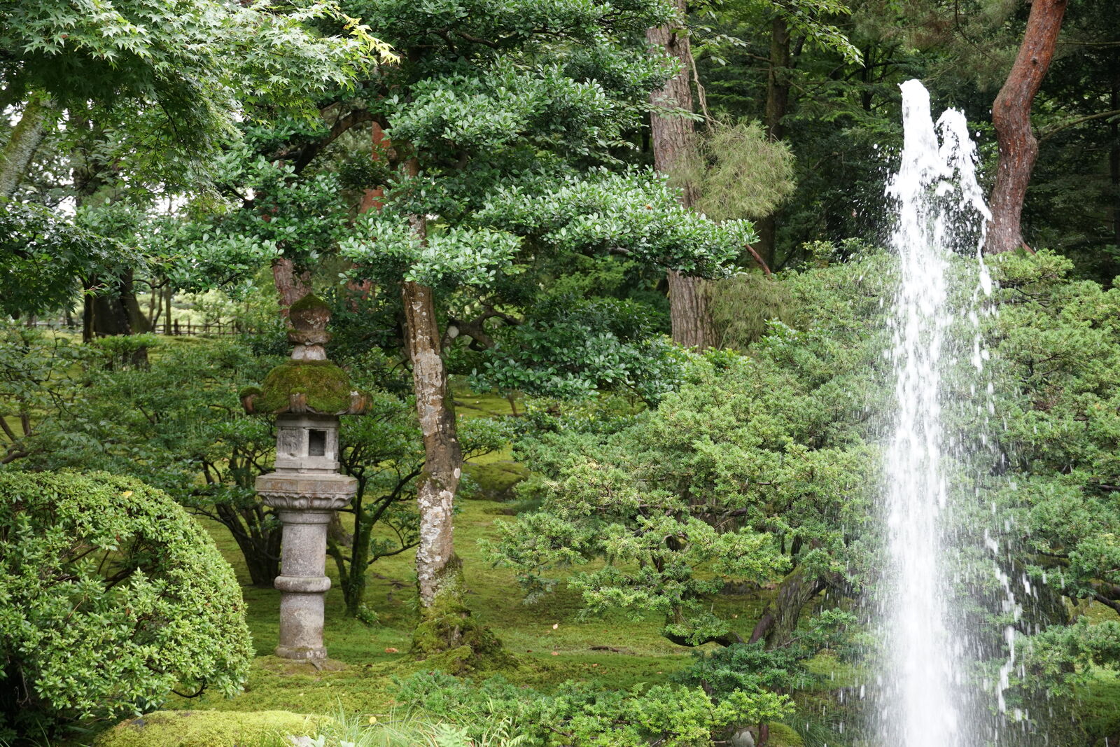 The famous natural-pressure fountain spraying upward beside a stone lantern