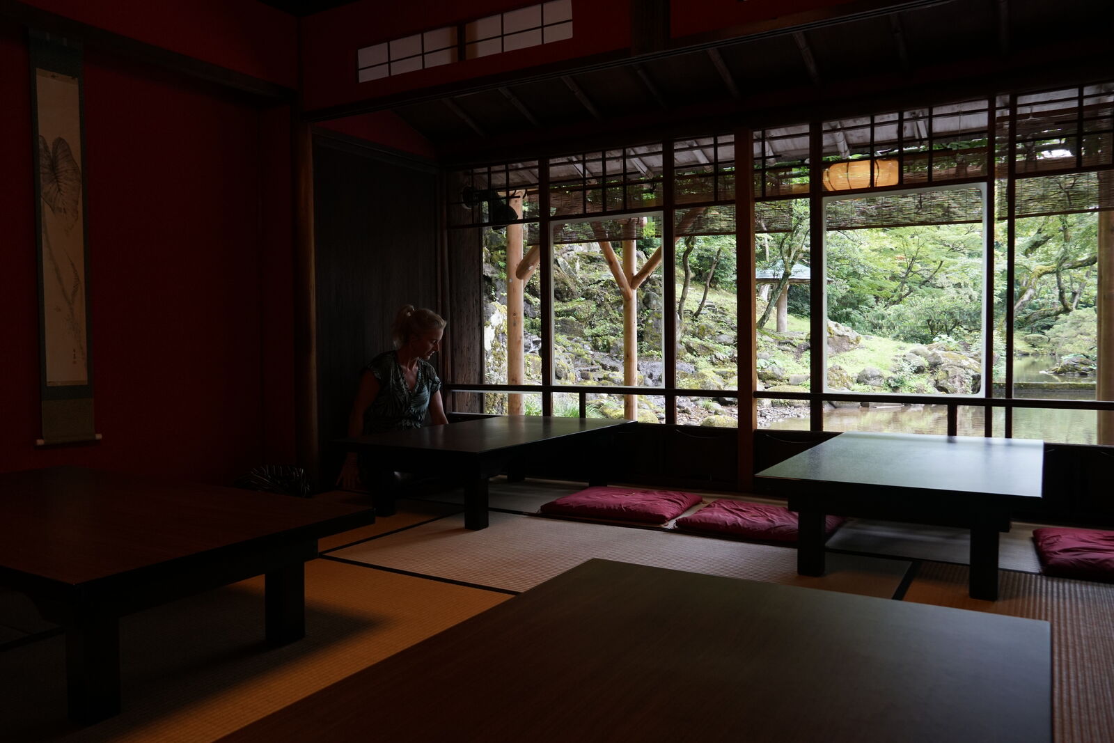 Tea house glimpsed through overhanging branches in moody green light