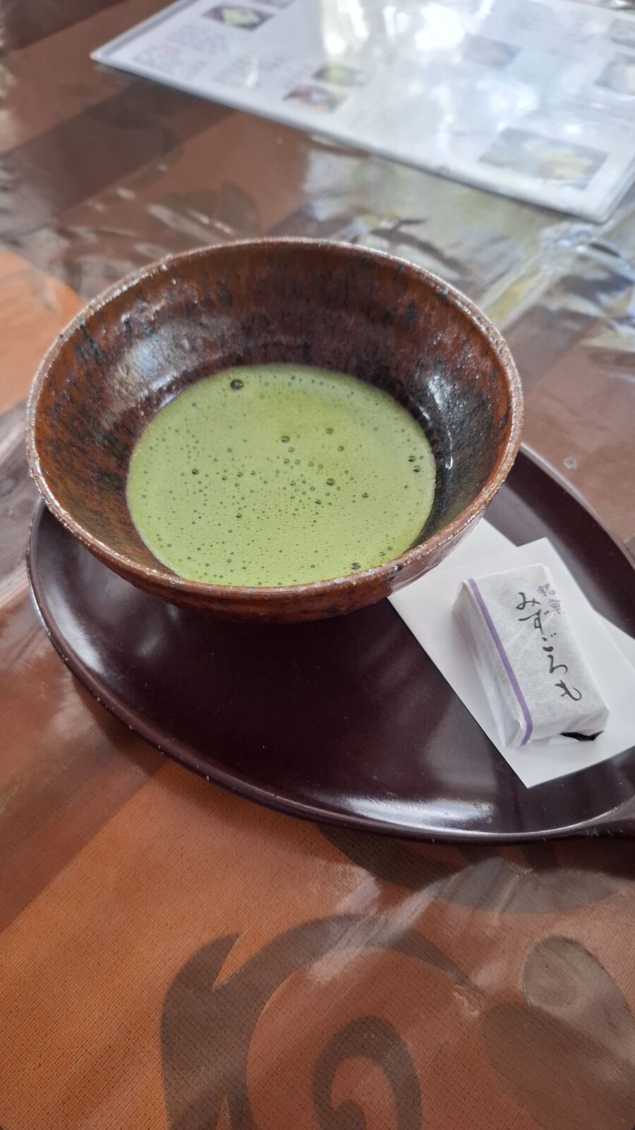 Matcha tea in a handmade ceramic bowl with a traditional sweet, served on a dark lacquer tray at the café