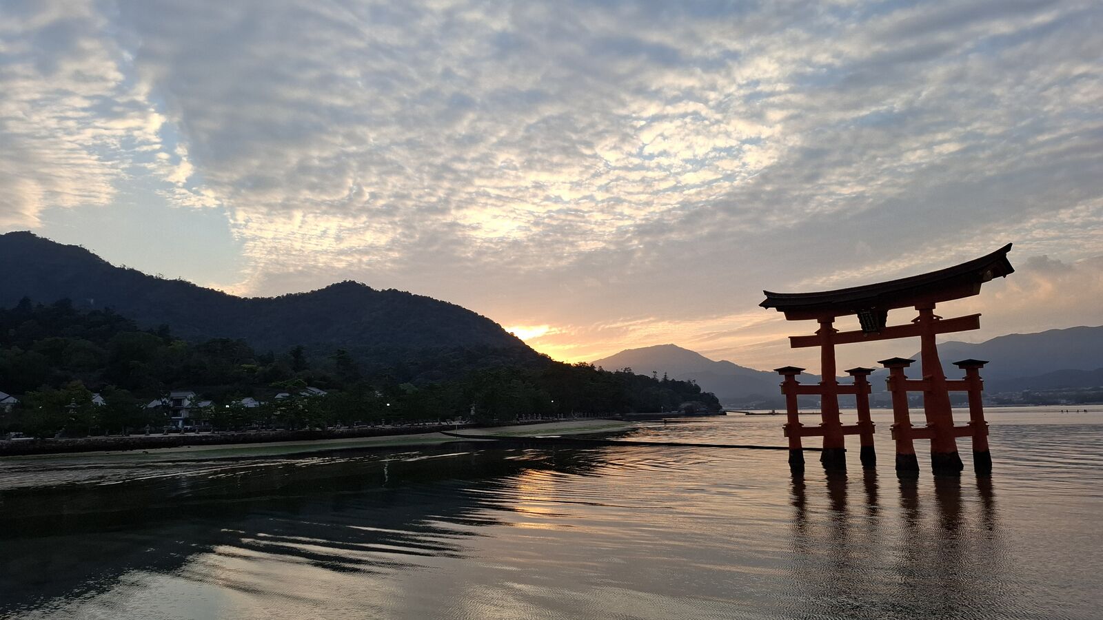 The floating torii of Itsukushima Shrine silhouetted against a golden sunset