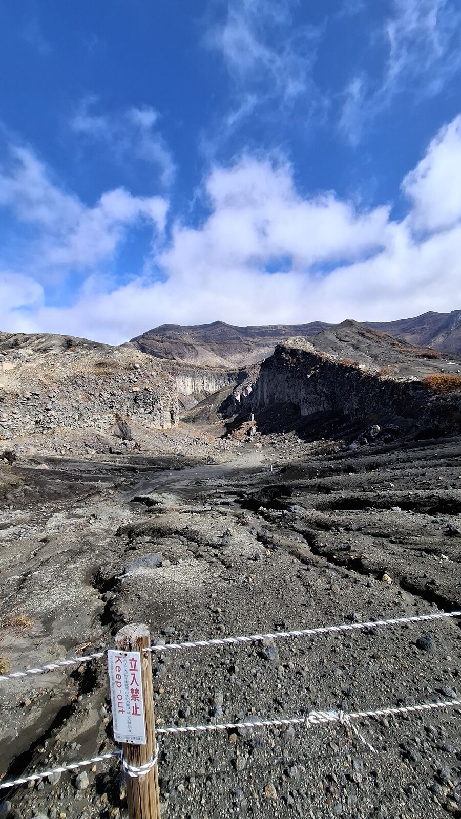 Keep Out barrier with the volcanic terrain stretching behind it, dark lava rock and ash creating patterns across the ground