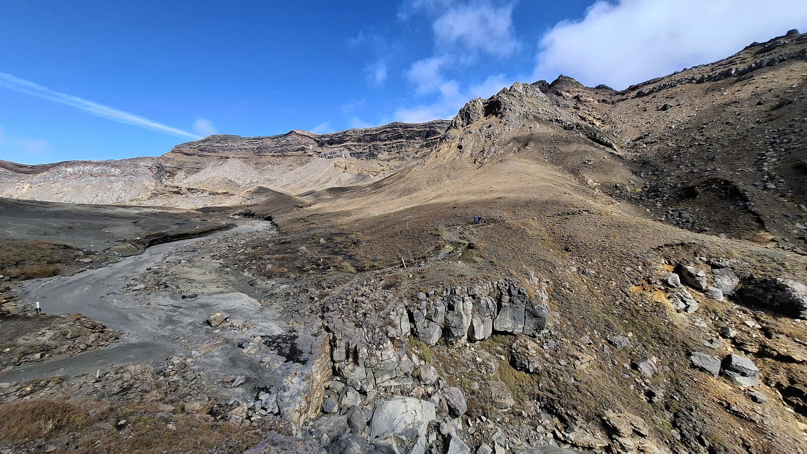 Volcanic rock formations in the caldera, eroded lava pillars and ash deposits creating an alien landscape under clear blue sky
