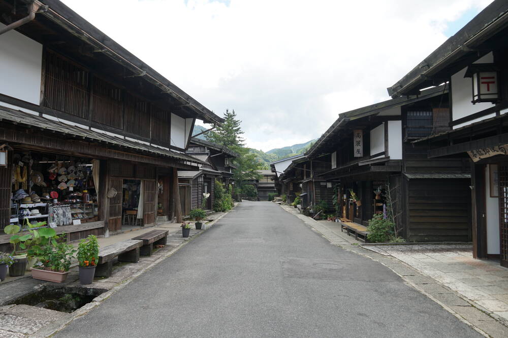 The main street of Tsumago post town, dark timber buildings lining an empty road with mountains behind