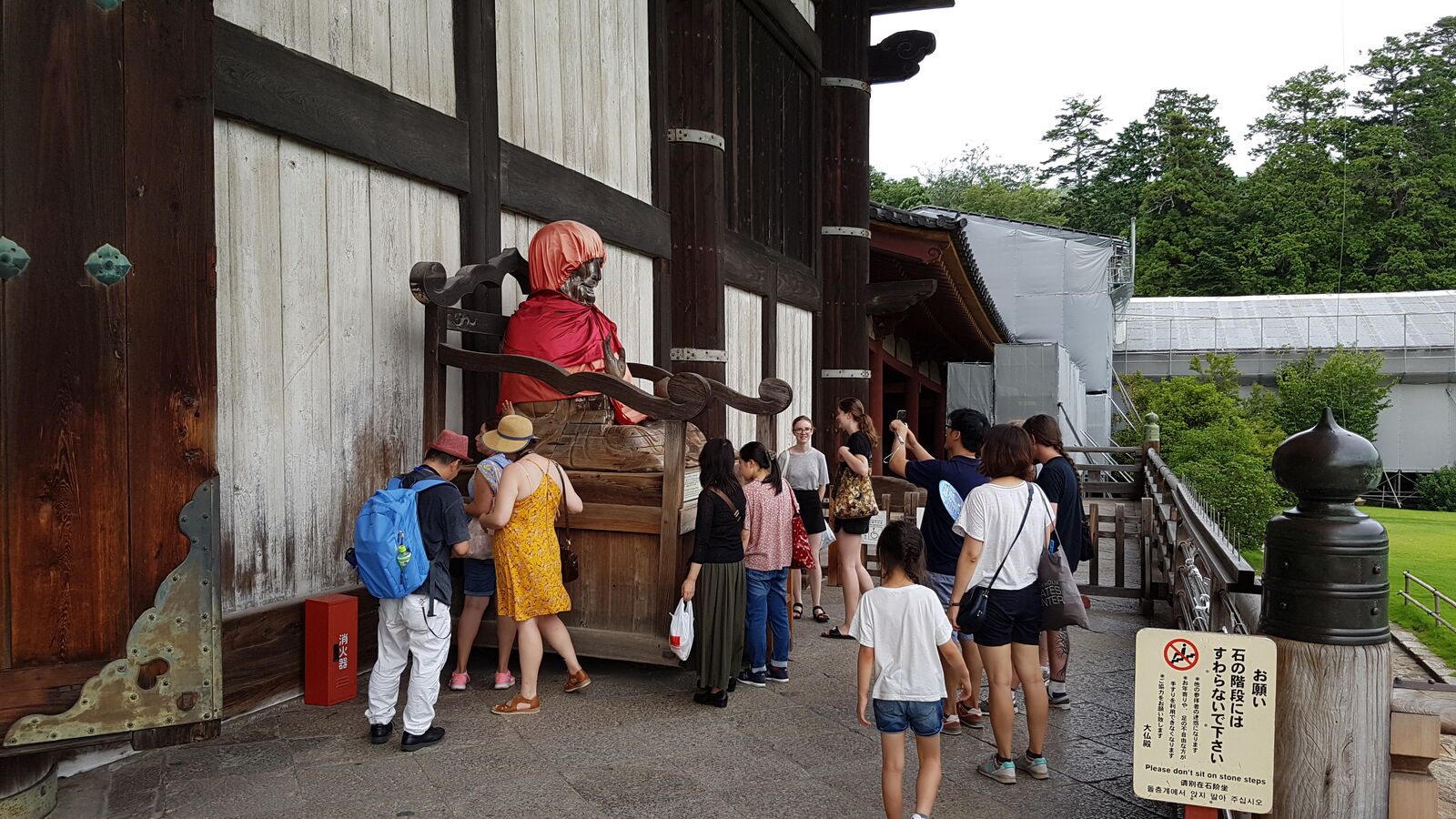 The Binzuru healing statue outside Todai-ji, the wooden figure draped in red cloth, visitors reaching out to touch it for good health