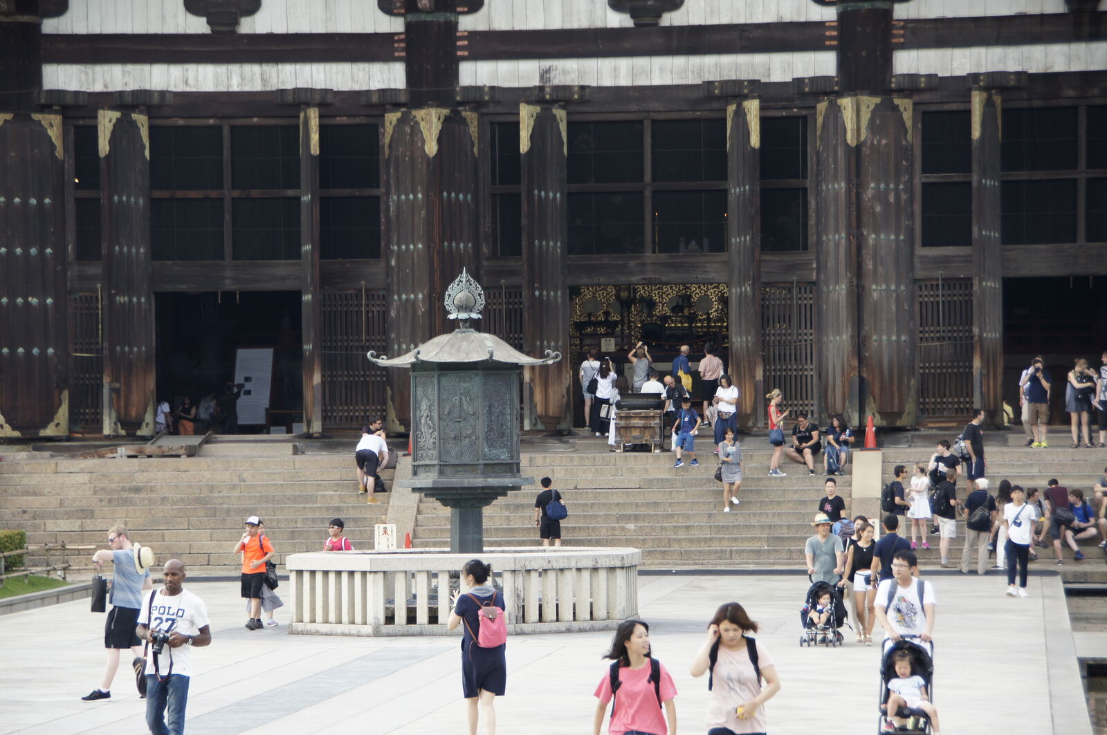 The courtyard in front of Todai-ji's entrance, a bronze lantern on a white stone platform in the center, visitors streaming in and out of the great hall