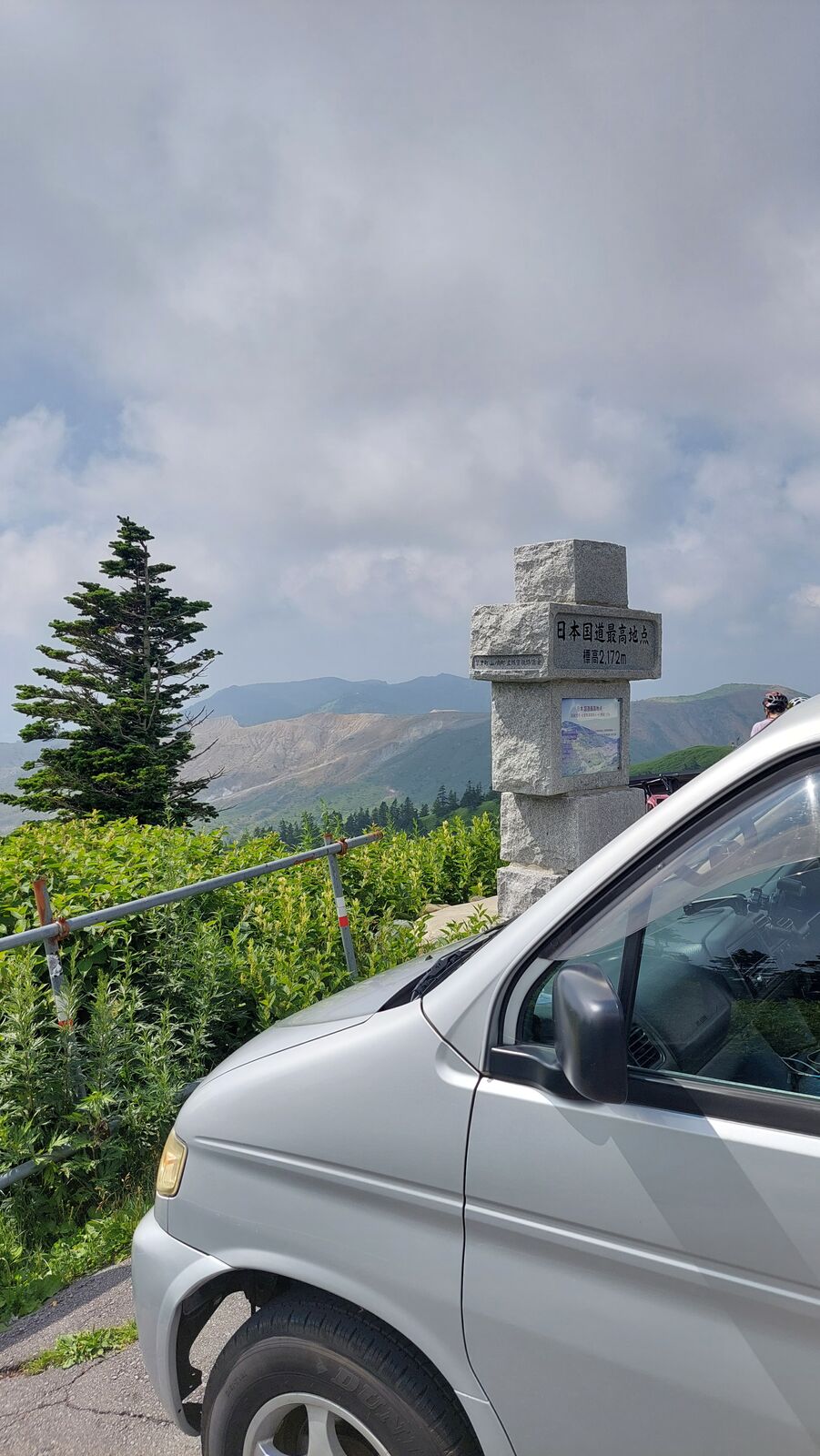 Campervan at the highest point monument on Route 292 with volcanic mountains behind
