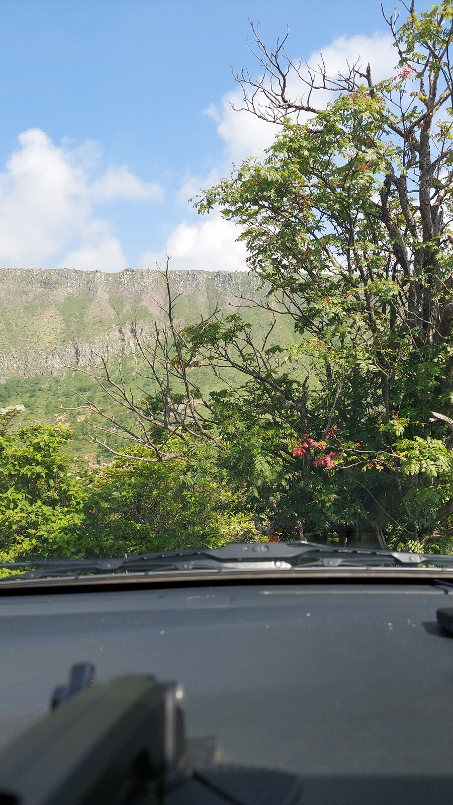 Campervan in the mountain landscape with green slopes and blue sky on the morning approach to the pass